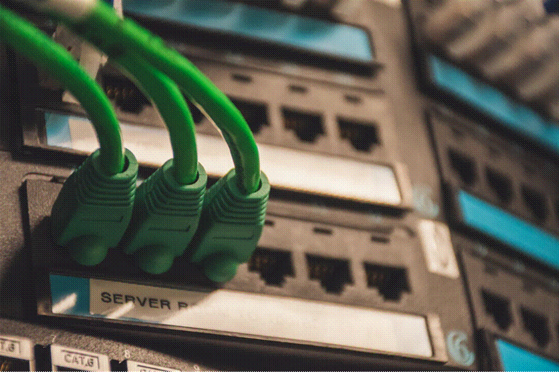 Title: Network hub with green indicator lights - Description: Close-up of a network hub with illuminated green ports, representing the AI-driven technology infrastructure powering the WISeR model.